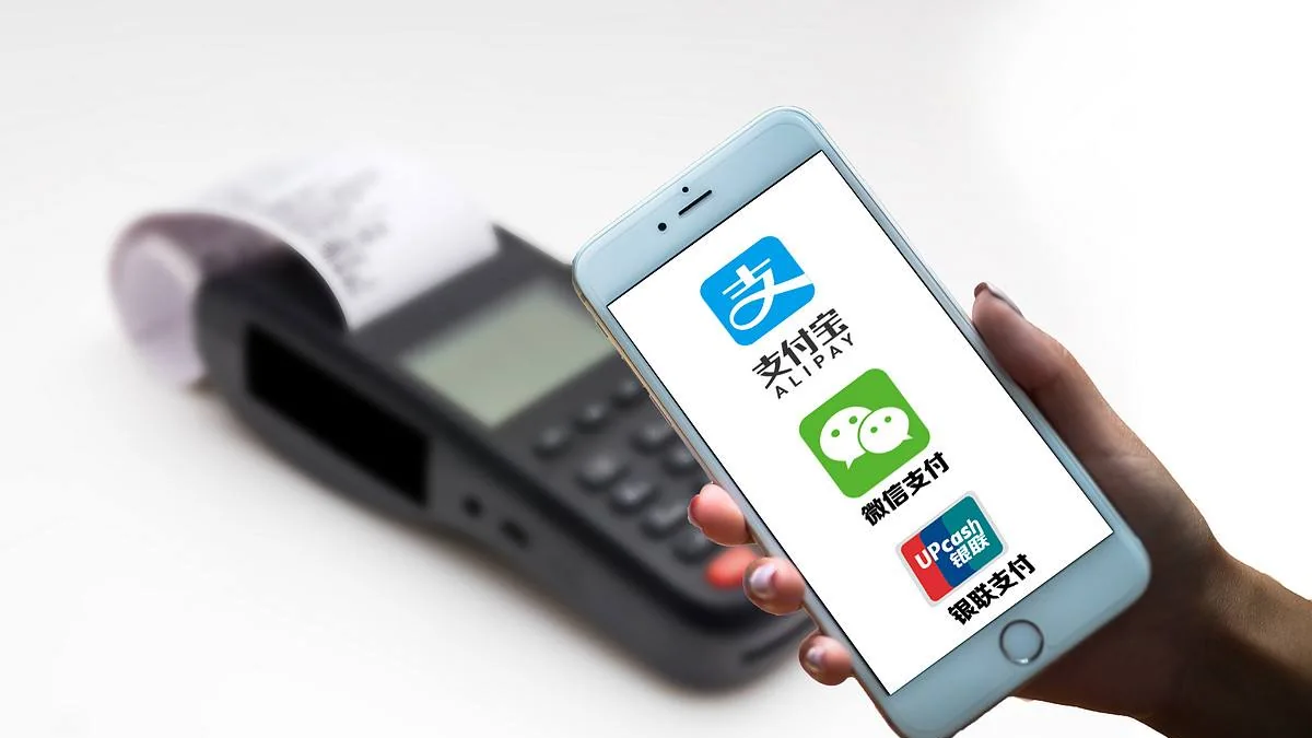 A phone showing Alipay and WeChat Pay logos beside a card reader