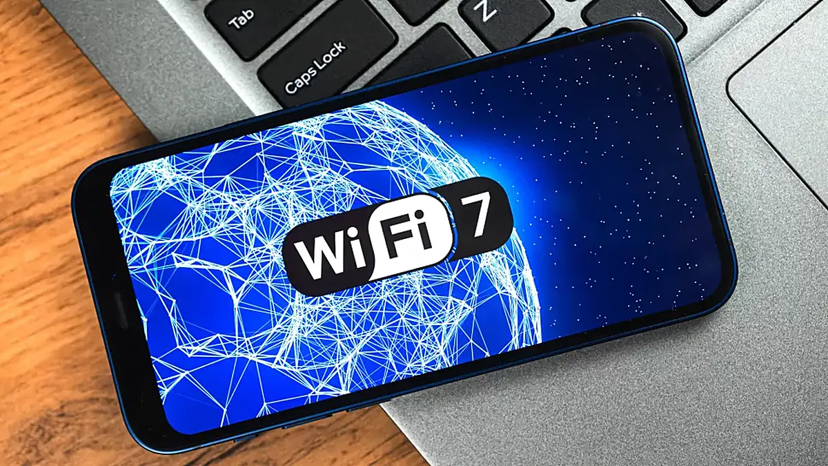 A phone screen glowing with the Wi-Fi 7 symbol above a laptop keyboard