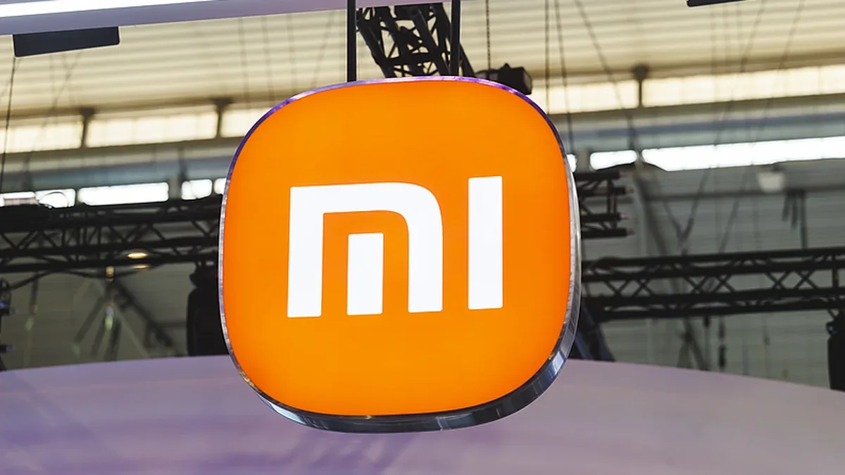 Glowing orange Xiaomi logo cube hanging above a trade show booth
